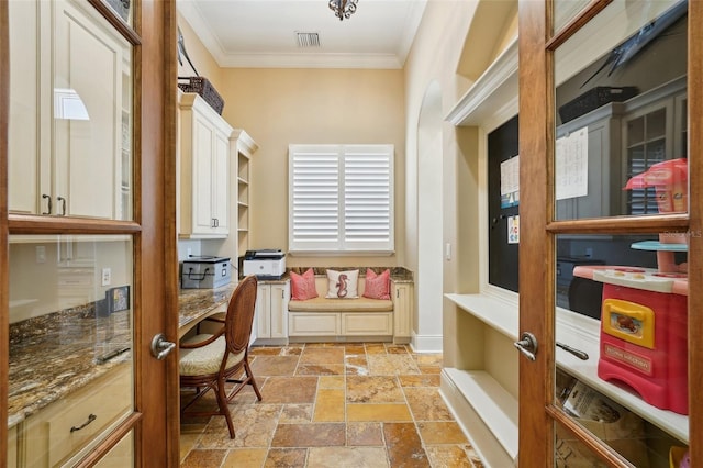 office featuring stone tile flooring, built in study area, visible vents, and crown molding