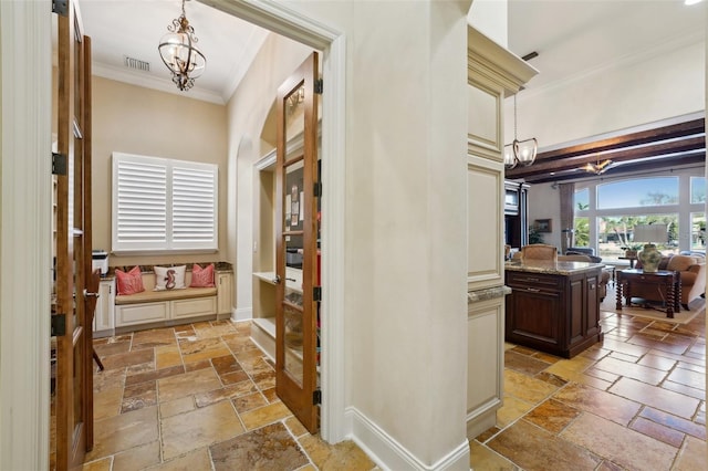 hall with stone tile floors, visible vents, baseboards, an inviting chandelier, and crown molding