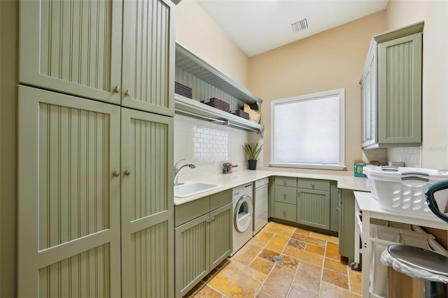 washroom featuring washer / dryer, a sink, visible vents, cabinet space, and stone tile flooring