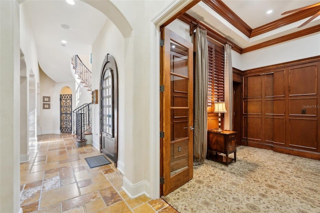 hallway with arched walkways, crown molding, stone tile floors, baseboards, and stairs