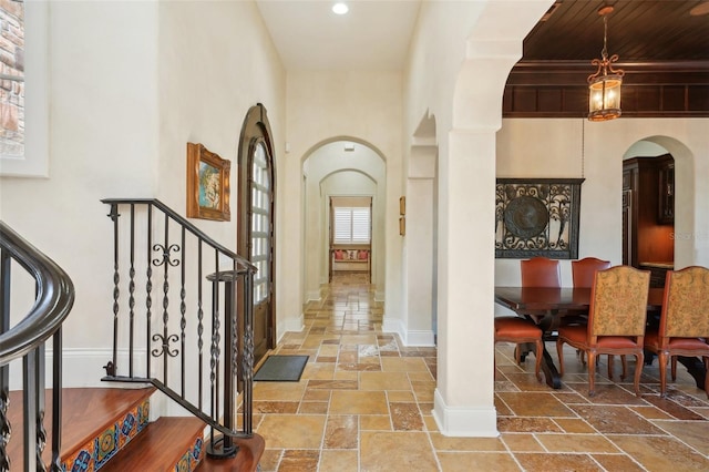 interior space featuring arched walkways, baseboards, stone tile floors, and stairs