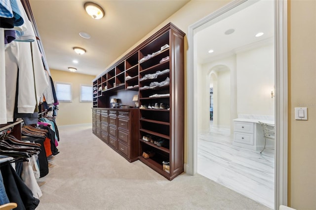 spacious closet with arched walkways and light colored carpet