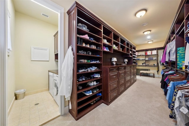 walk in closet with visible vents, washer and clothes dryer, and light colored carpet