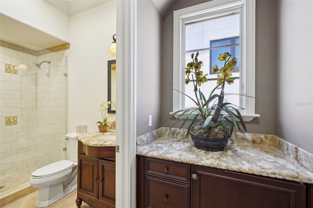 bathroom featuring toilet, tiled shower, and vanity