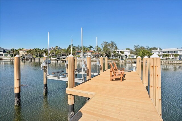 view of dock featuring a water view, boat lift, and a residential view