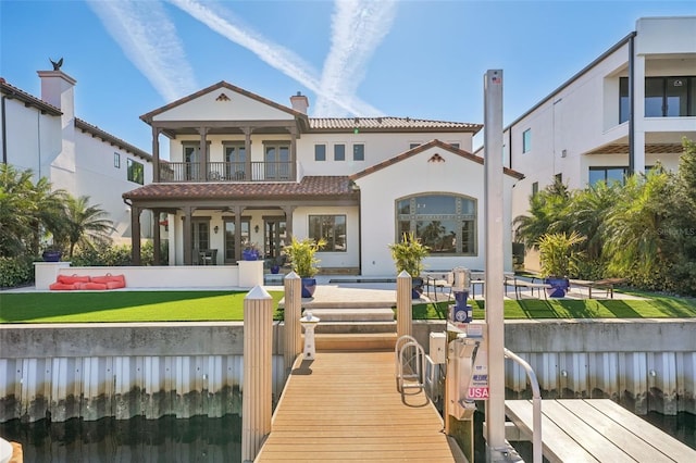 rear view of property featuring a tile roof, a balcony, and stucco siding