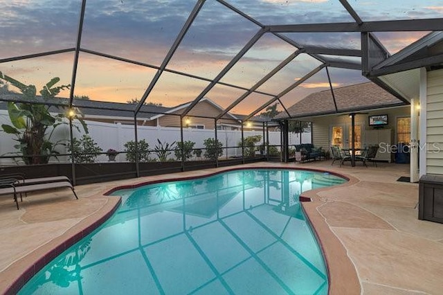 pool at dusk featuring a lanai and a patio area