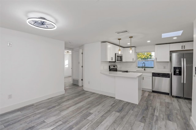 kitchen featuring appliances with stainless steel finishes, white cabinetry, sink, hanging light fixtures, and kitchen peninsula