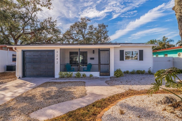 ranch-style home featuring central AC unit and a garage