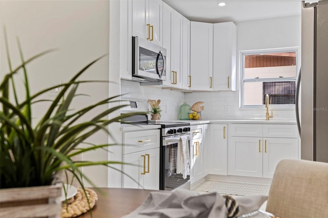 kitchen featuring tasteful backsplash, sink, white cabinets, and appliances with stainless steel finishes