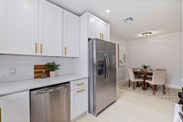 kitchen with stainless steel appliances, white cabinetry, light stone counters, and decorative backsplash