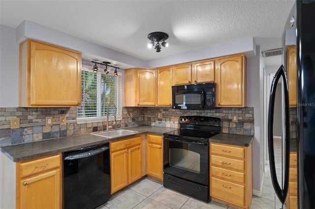 kitchen featuring tasteful backsplash, light tile patterned floors, sink, and black appliances