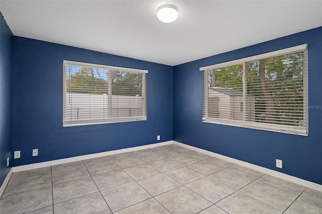 tiled empty room featuring plenty of natural light and a textured ceiling