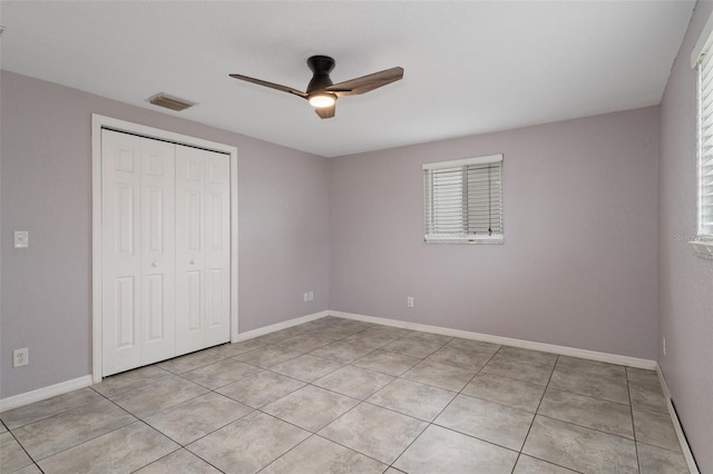 unfurnished bedroom with light tile patterned flooring, ceiling fan, and a closet