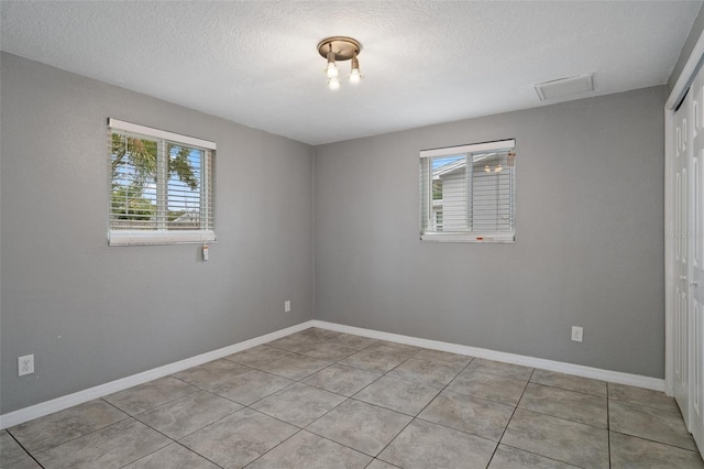 tiled spare room with a textured ceiling