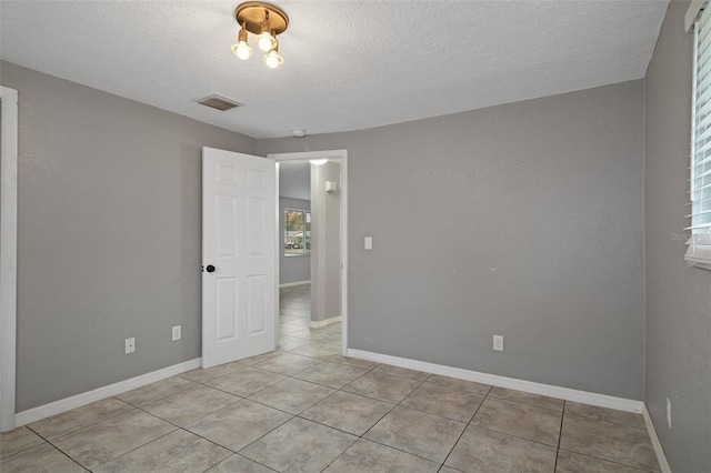 tiled spare room with a textured ceiling