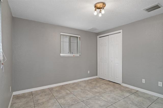 unfurnished bedroom featuring light tile patterned flooring, a closet, and a textured ceiling