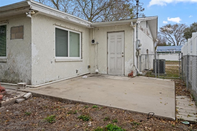 view of exterior entry featuring cooling unit and a patio