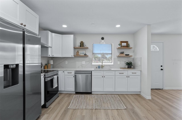 kitchen with sink, backsplash, white cabinets, and appliances with stainless steel finishes