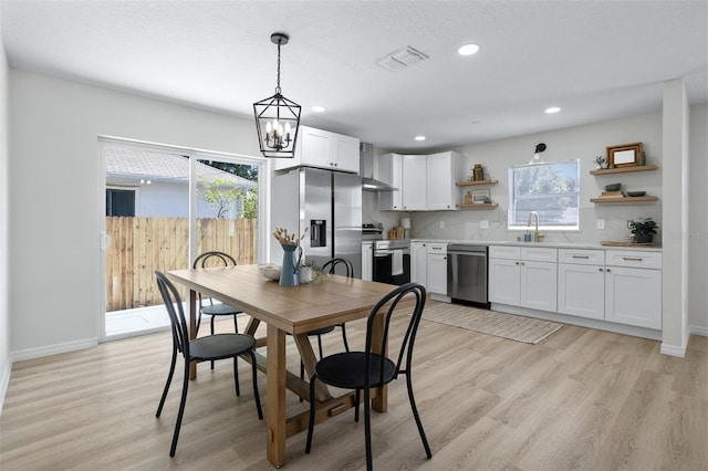 dining area with a wealth of natural light, sink, and light wood-type flooring