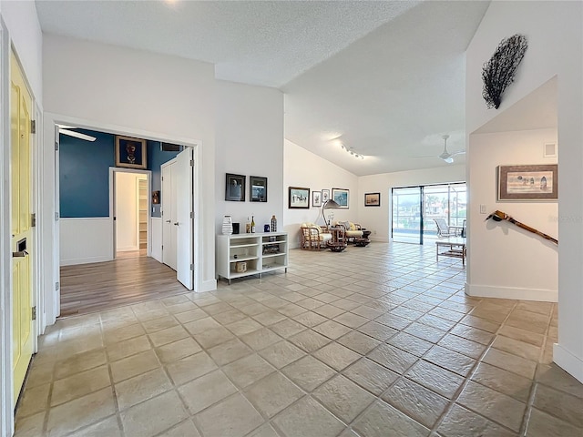 unfurnished living room with vaulted ceiling, a textured ceiling, and ceiling fan