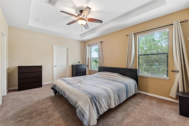 bedroom featuring carpet floors, a raised ceiling, and ceiling fan