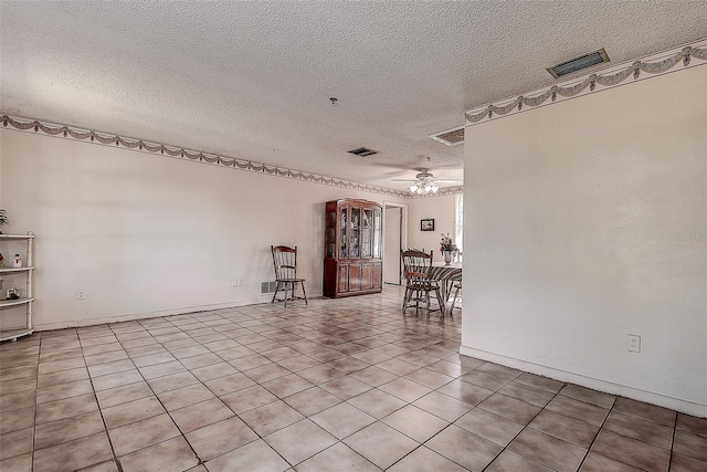 tiled empty room with ceiling fan and a textured ceiling