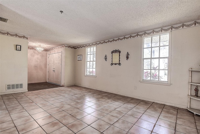 empty room with light tile patterned floors and a textured ceiling