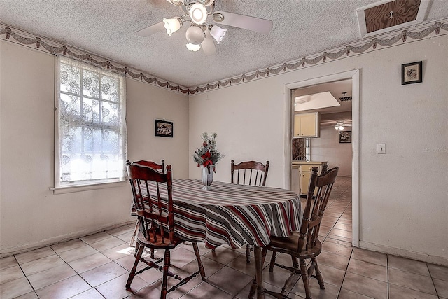 tiled dining room with ceiling fan and a textured ceiling