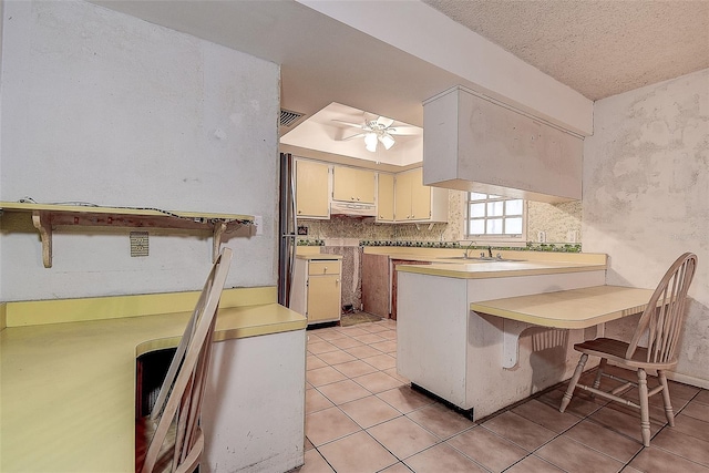 kitchen with sink, light tile patterned floors, a kitchen breakfast bar, kitchen peninsula, and decorative backsplash