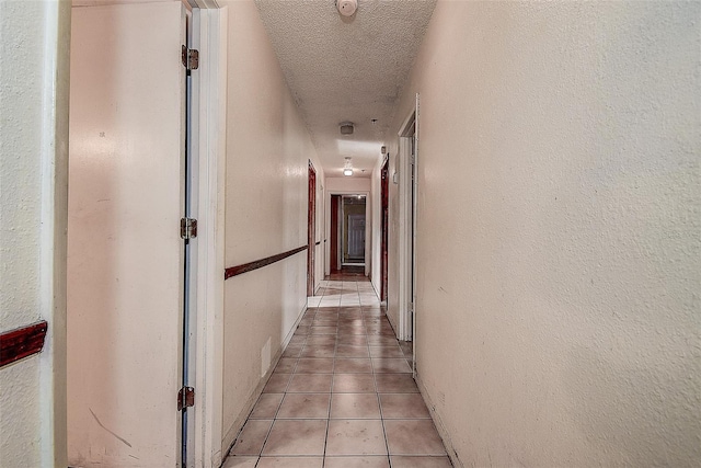 hallway with light tile patterned floors and a textured ceiling