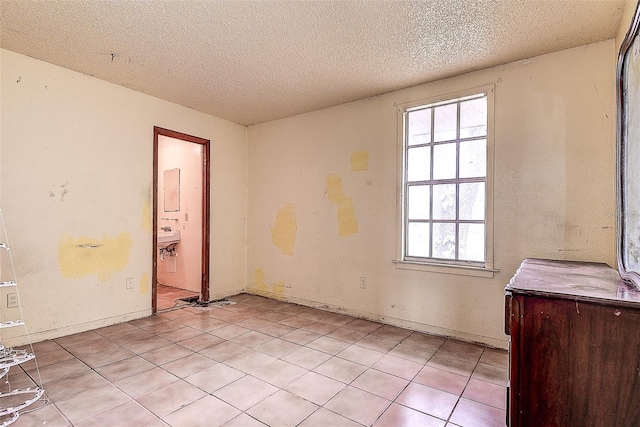 tiled empty room featuring a textured ceiling