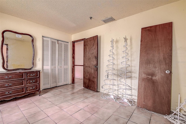 bedroom with light tile patterned flooring, a closet, and a textured ceiling