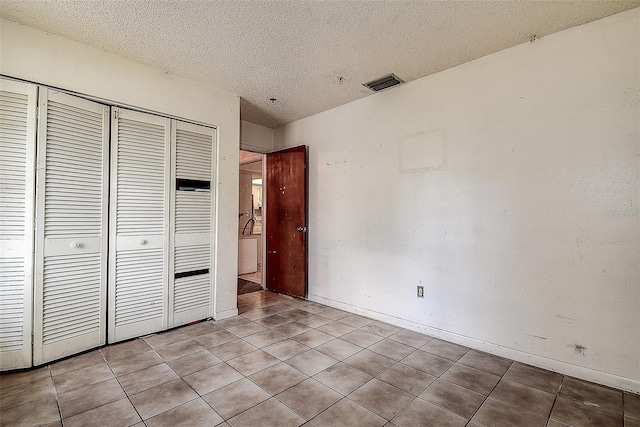 unfurnished bedroom featuring light tile patterned flooring, a textured ceiling, and a closet