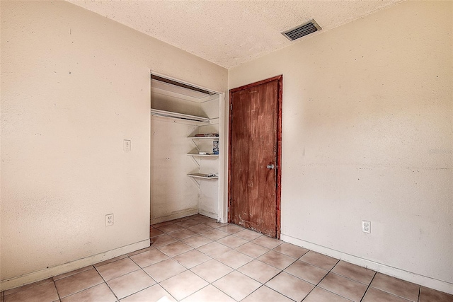 unfurnished bedroom with light tile patterned floors, a textured ceiling, and a closet