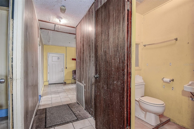 bathroom featuring tile patterned flooring, a textured ceiling, and toilet