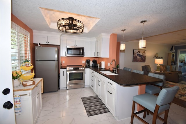 kitchen with white cabinetry, appliances with stainless steel finishes, kitchen peninsula, and sink