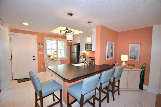 kitchen with white cabinetry, appliances with stainless steel finishes, sink, and a breakfast bar