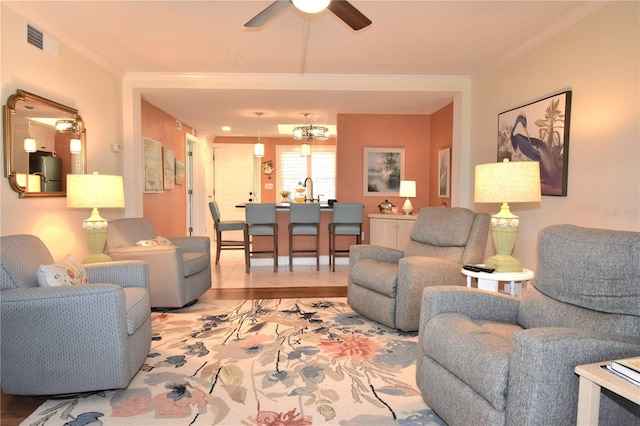 living room featuring ornamental molding and ceiling fan with notable chandelier