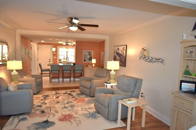 living room with ceiling fan, a healthy amount of sunlight, ornamental molding, and light hardwood / wood-style flooring