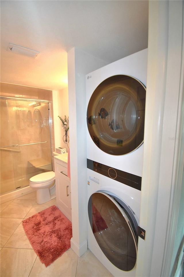 laundry area featuring stacked washer and dryer and light tile patterned floors