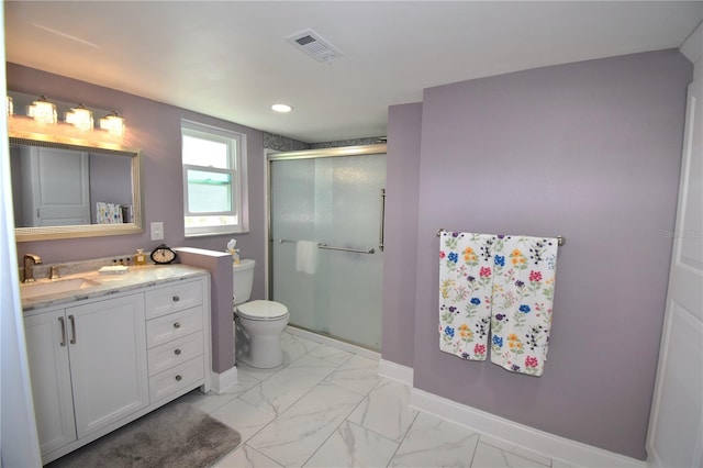 bathroom featuring vanity, a shower with shower door, and toilet