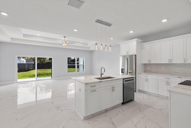 kitchen with stainless steel appliances, pendant lighting, a center island with sink, and white cabinets