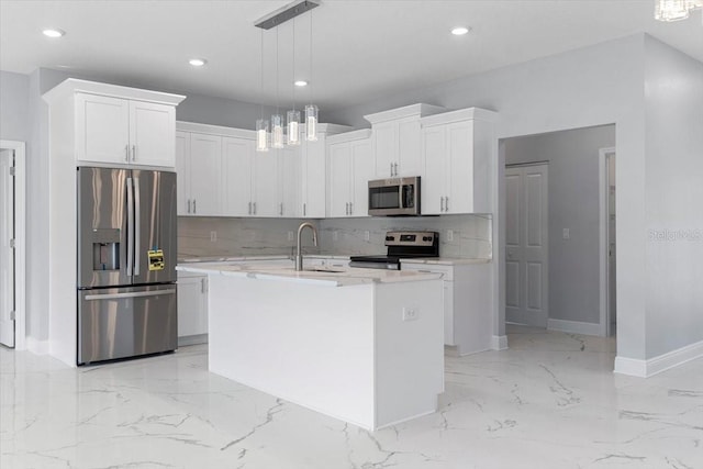 kitchen with stainless steel appliances, decorative light fixtures, an island with sink, and white cabinets