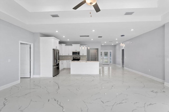 kitchen with stainless steel appliances, white cabinetry, a kitchen island, and decorative light fixtures