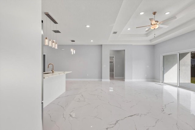 empty room with ceiling fan, a tray ceiling, and sink