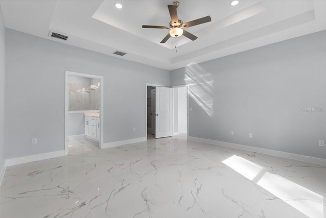 empty room with ceiling fan and a tray ceiling