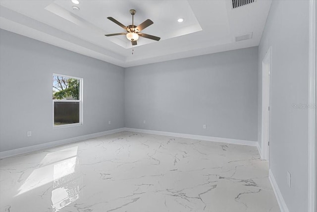 spare room with ceiling fan and a tray ceiling