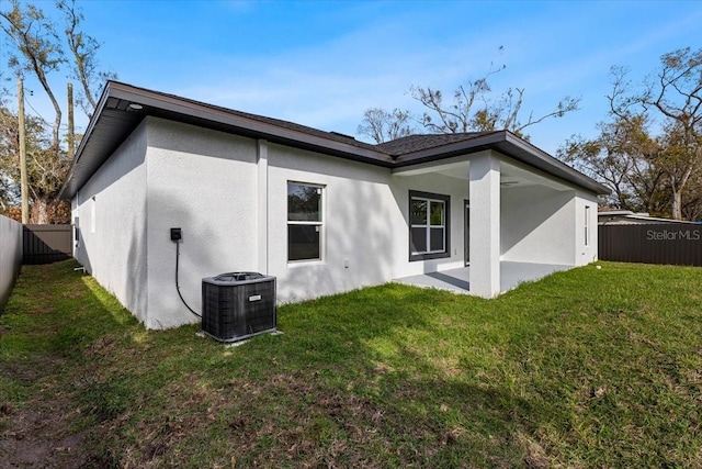 back of house with cooling unit and a lawn