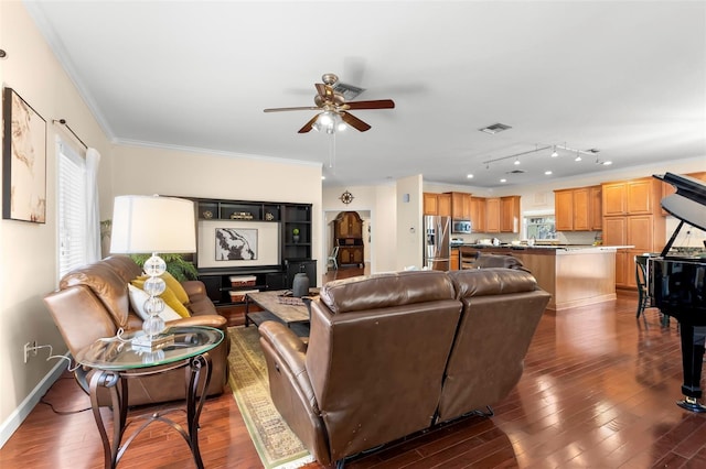 living room with crown molding, dark wood-type flooring, track lighting, and ceiling fan